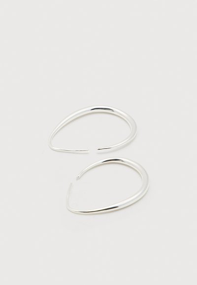 Ζευγάρι λεία, λαμπερά ασημένια σκουλαρίκια σε σχήμα δάκρυ με ανοιχτά άκρα, εκτεθειμένα σε απλό λευκό φόντο.