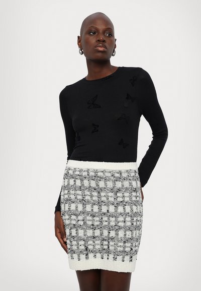 Black long-sleeve top with textured butterfly motifs, paired with a fitted knit skirt in a checkered black and white pattern.