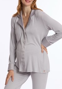Lichtgrijs loungewear-set met een knoopsluiting-top met een kraag en lange mouwen, gecombineerd met bijpassende broek; glad, zacht materiaal.