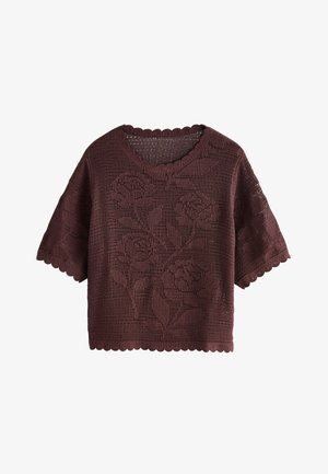 Haut marron crocheté à manches courtes avec bords festonnés et motif floral intégré dans le dessin tricoté.