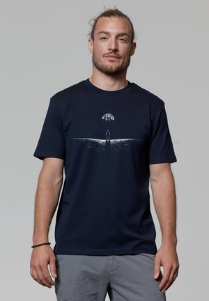Navy blue cotton t-shirt featuring a graphic print of a figure standing before a water surface, under a stylized moon and stars.