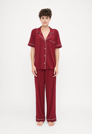 Burgundy pajama set made of soft fabric, featuring a short-sleeve shirt with white piping and matching loose-fit pants.