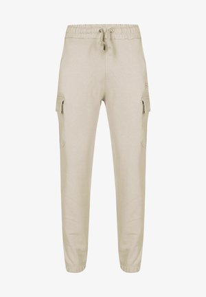 Béžové tepláky s šňůrkou v pase, bočními cargo kapsami a manžetami na kotnících, vyrobené z měkkého materiálu se hladkým povrchem.