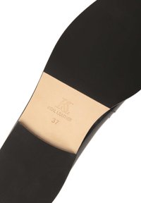 Black leather shoe sole featuring a smooth finish, engraved “K&S REAL LEATHER,” size 37, with a light tan underside.