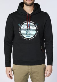 Svart hoodie med en framgrafik som har ett cirkulärt motiv i blått och vitt, ficka med dragkedja på sidan och röda snören.