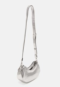 Piccola borsa a spalla metallica argentata con un motivo a crocantino, tracolla regolabile e scomparto zip visibile.