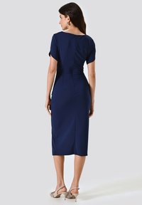 Dunkelblaues, tailliertes Kleid mit kurzen Ärmeln und Midi-Länge. Verfügt über einen Rückenreißverschluss und dezente Falten für zusätzliche Textur.