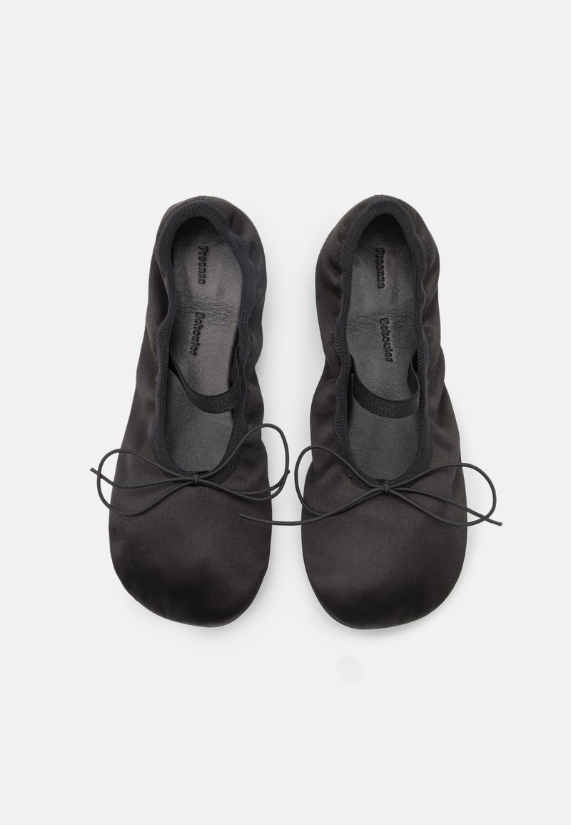 Bailarinas negras de tela suave con punta redonda y un delgado lazo en la parte delantera. Textura suave y diseño minimalista.
