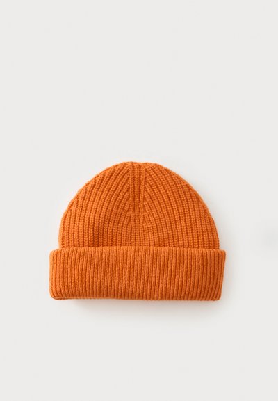 Bonnet en tricot orange avec revers plié, présenté sur un fond gris clair uni.
