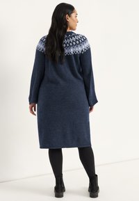 Knielanges, navyblaues Strickkleid mit langen Ärmeln und einem gemusterten Schulterbereich in Hellblau. Es hat eine lockere Passform und einen runden Halsausschnitt.