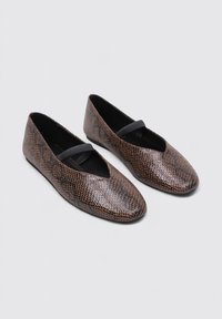 Brogues en cuir imprimé serpent marron avec un bout pointu, une sangle noire croisée et une texture lisse. Design léger avec un talon minimal.