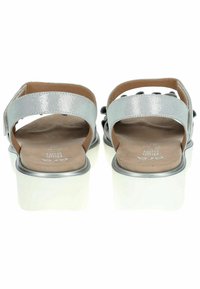 Zilveren sandalen met rugband van leer met een metallic glans, gevoerd voetbed en een dikke witte plateauzool. Bevat zwarte decoratieve accenten.