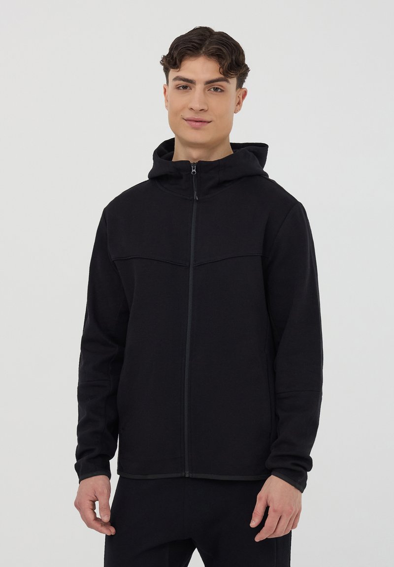 Felpa nera con zip e cappuccio, caratterizzata da una texture liscia e un audace design delle cuciture sul petto. Vestibilità slim con maniche lunghe.