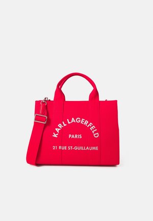 Bright red tote bag with dual handles and adjustable shoulder strap, white "Karl Lagerfeld Paris 21 Rue St-Guillaume" text on front center.