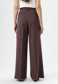 Wijdere broek in een gedempte mauve kleur, met een knoopsluiting, twee achterzakken en een gladde, gestructureerde stof.