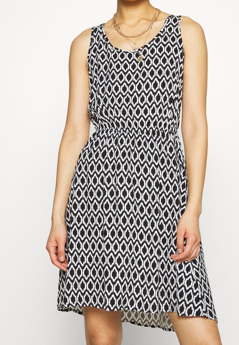 Robe noire et blanche à motif, au design sans manches, avec une taille élastique et un ourlet fluide, présentant une texture à imprimé géométrique.