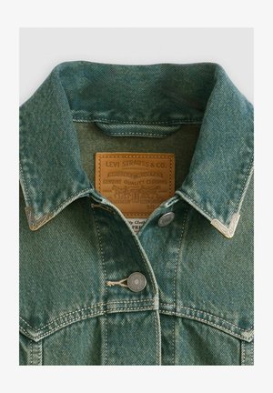 Jeansjacke in verblasstem Türkis mit spitzem Kragen, silbernen Knöpfen und einem Lederetikett mit Branddetails.