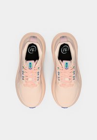 Baskets de sport rose clair avec une tige texturée, des lacets colorés en bleu et violet, et une semelle intérieure noire portant un logo et la taille.