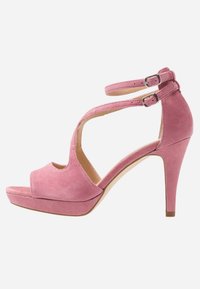 Sandalia de tacón alto de ante rosa con punta abierta, doble tira en el tobillo y suela de plataforma. Presenta una forma contorneada y textura suave.