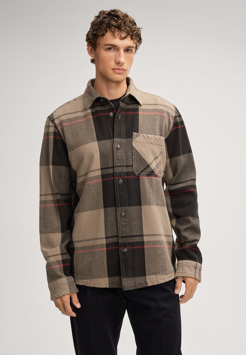Brązowa i czarna flanelowa koszula w kratę z zapięciem na guziki, spiczastym kołnierzem i kieszenią. Charakteryzuje się czerwonymi liniami i teksturowanym wykończeniem materiału.