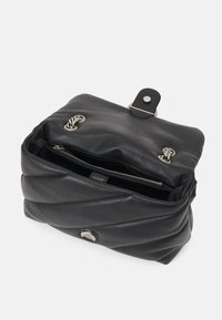 Zwarte lederen tas met een gequilt design, voorzien van een bovenklep met sluiting, zilveren hardware en een binnenzak met rits voor organisatie.