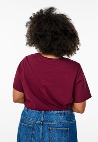 T-shirt en coton bordeaux à manches courtes et col rond, associé à une jupe en denim taille haute avec deux poches arrière.