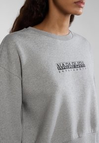 Grijze sweatshirt met een geribbelde ronde halslijn en een gedurfde zwarte "NAPAPIJRI geographic" logo aan de voorkant. Zacht, textuurstof.