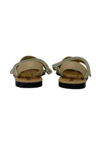 Sandali beige con due cinturini regolabili, una parte superiore liscia e una suola nera testurizzata. Caratterizzati da una soletta naturale con stampa del marchio.