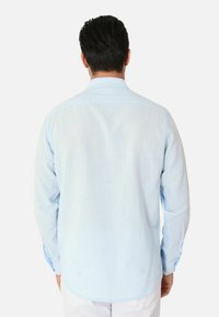 Camicia azzurra a maniche lunghe realizzata in morbido cotone, con colletto a bottoni e finiture cucite con orlo arrotondato.