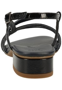 Černé lakované sandály s nastavitelným páskem kolem kotníku, hladkou polstrovanou stélkou a nízkým blokovým podpatkem. Obsahují texturovanou podrážku.