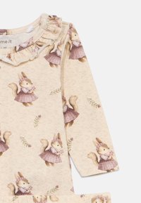 Vestido de manga longa cream com colarinho franzido, apresentando estampas de esquilos em vestidos e acentos florais em tecido suave e texturizado.