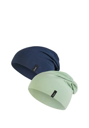 Two soft cotton slouchy beanies in navy blue and light green, each with a small black brand tag on the side.
