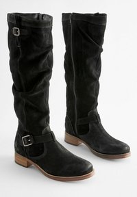 Bottes noires en suède montantes jusqu'au genou avec une fermeture éclair sur le côté, un accent à boucle et une tige texturée. Les talons en bois carré offrent de la stabilité.