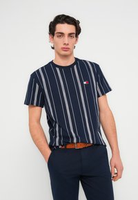 Μπλουζάκι με ναυτικό μπλε ρίγες από βαμβάκι, με λευκές κάθετες ρίγες και μικρό λογότυπο στο στήθος. Κοντά μανίκια και στρογγυλή λαιμόκοψη.