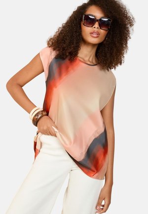 Top fluido e con maniche corte in gradiente da pesco a rosso con accenti neri, caratterizzato da una texture liscia e una vestibilità rilassata, infilato in pantaloni a gamba larga color crema.