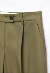 Pantalons ajustés vert olive avec une taille plate, deux poches latérales et une fermeture à bouton unique. Tissu lisse avec une texture subtile.