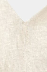 Gros plan d’un tissu en lin couleur crème avec une couture centrale et un décolleté en V.
