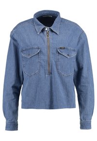 Blå denimskjorta med lång ärm, krage, halv dragkedja framtill och två knappade bröstfickor.