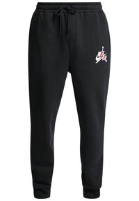 Černé bavlněné tepláky s elastickým pasem a nastavovací šňůrkou. Na levém stehně je bílé/červené logo Nike Air.