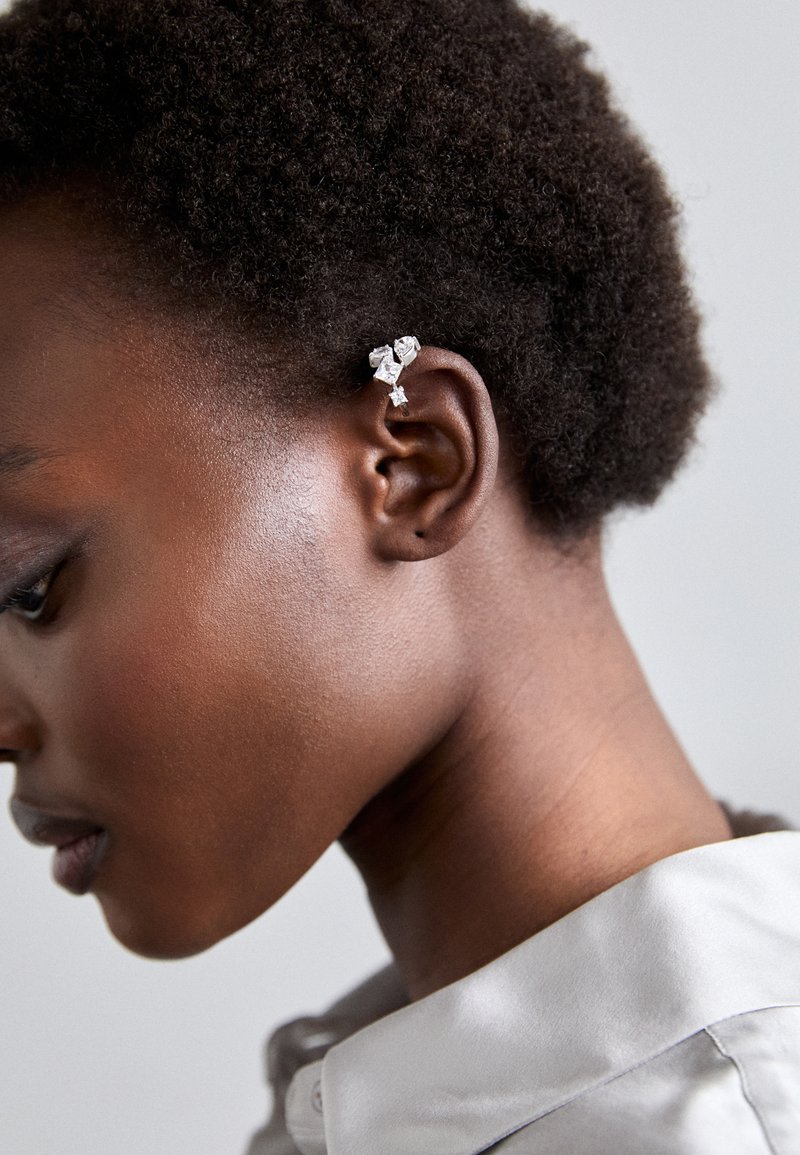 Ασημένιο αυτί φυσιγγίου με πολλούς γωνιακούς κρυστάλλους συνδεδεμένους στο εξωτερικό του αυτιού, με μινιμαλιστικό σχέδιο και μεταλλική λάμψη.