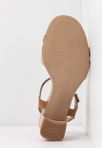 Sandale en cuir marron avec une sangle réglable, semelle en caoutchouc texturée et motif antidérapant. Talon plat pour plus de stabilité. Taille 37.