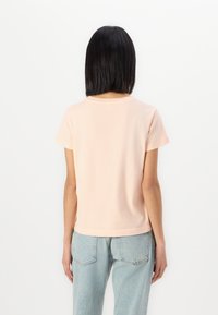 Tricou din bumbac roz deschis, cu mânecă scurtă, guler rotund, croială dreaptă �și detalii minime de cusătură la tiv și mâneci.