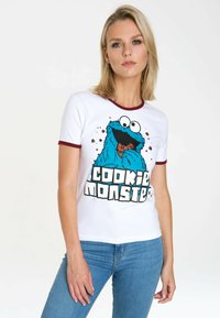 White cotton t-shirt with maroon trim, featuring a blue Cookie Monster graphic and bold "COOKIE MONSTER" text. Worn with denim jeans.