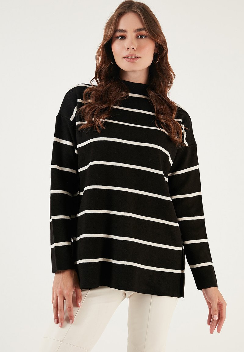 Pulover cu dungi negre și linii orizontale albe, design oversize, guler înalt și textură țesută. Prezintă mâneci lungi și slituri laterale.