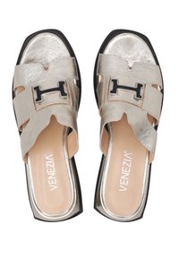 Gouden metalen slide-sandalen met een uitsnijdesign, met een accent van zwart hardware en een licht tan gevoerde inlegzool. Rond de neus en chunky hak.