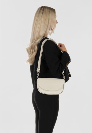 Sac à bandoulière en cuir couleur crème avec un rabat arrondi, une sangle réglable et des éléments en métal argenté. Fini texturé, conception compacte, style minimaliste.