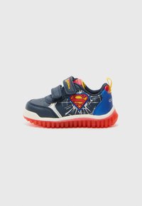 Baskets pour enfants bleu marine avec une semelle rouge, des accents blancs, des straps Velcro et un logo Superman sur le côté avec un design explosif.