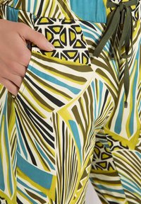 Gemusterte Hosen in den Farben Grün, Blau und Creme mit abstrakten Blattdesigns. Sie verfügen über einen Kordelzugbund und Seitentaschen. Weicher Stofftextur.