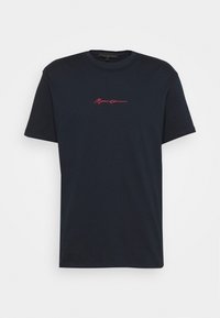 Marinblå bomulls t-shirt med korta ärmar, med en röd broderad logotyp på framsidan. Rund halsringning, avslappnad passform, slät textur.