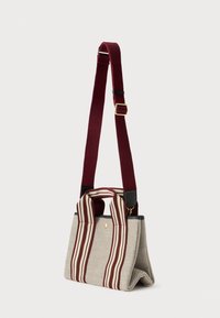 Μπεζ τσάντα tote από ύφασμα με χερούλια ριγέ σε μπορντό και λευκό, και ρυθμιζόμενη μπορντό χοντρή ζώνη ώμου με χρυσό κούμπωμα.